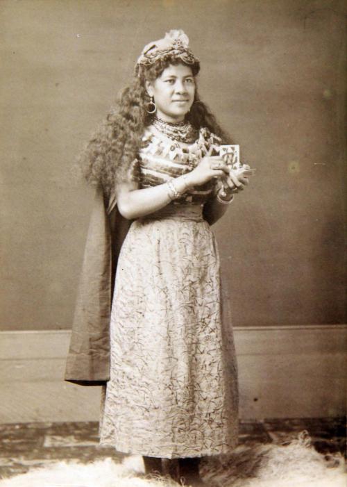 Standing Samoan woman holding playing cards.