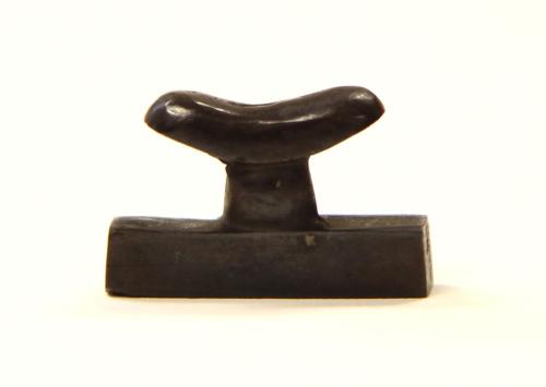 Amulet in form of miniature headrest